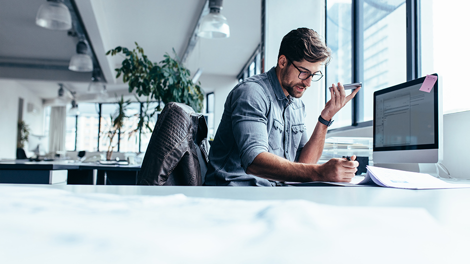 Businessman holding smart phone and working in office.