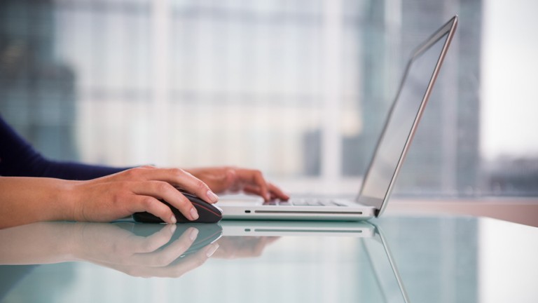 Business woman typing on a table infront of a window