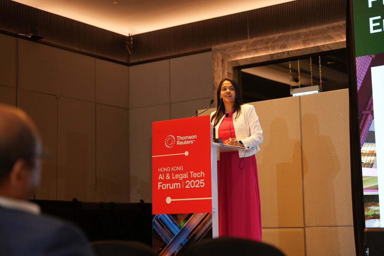 Speaker at a podium addressing attendees at the Hong Kong AI & Legal Tech Forum 2025.