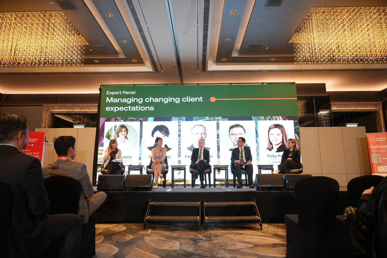Panel of experts seated on stage under a banner titled “Managing changing client expectations” at a conference event.