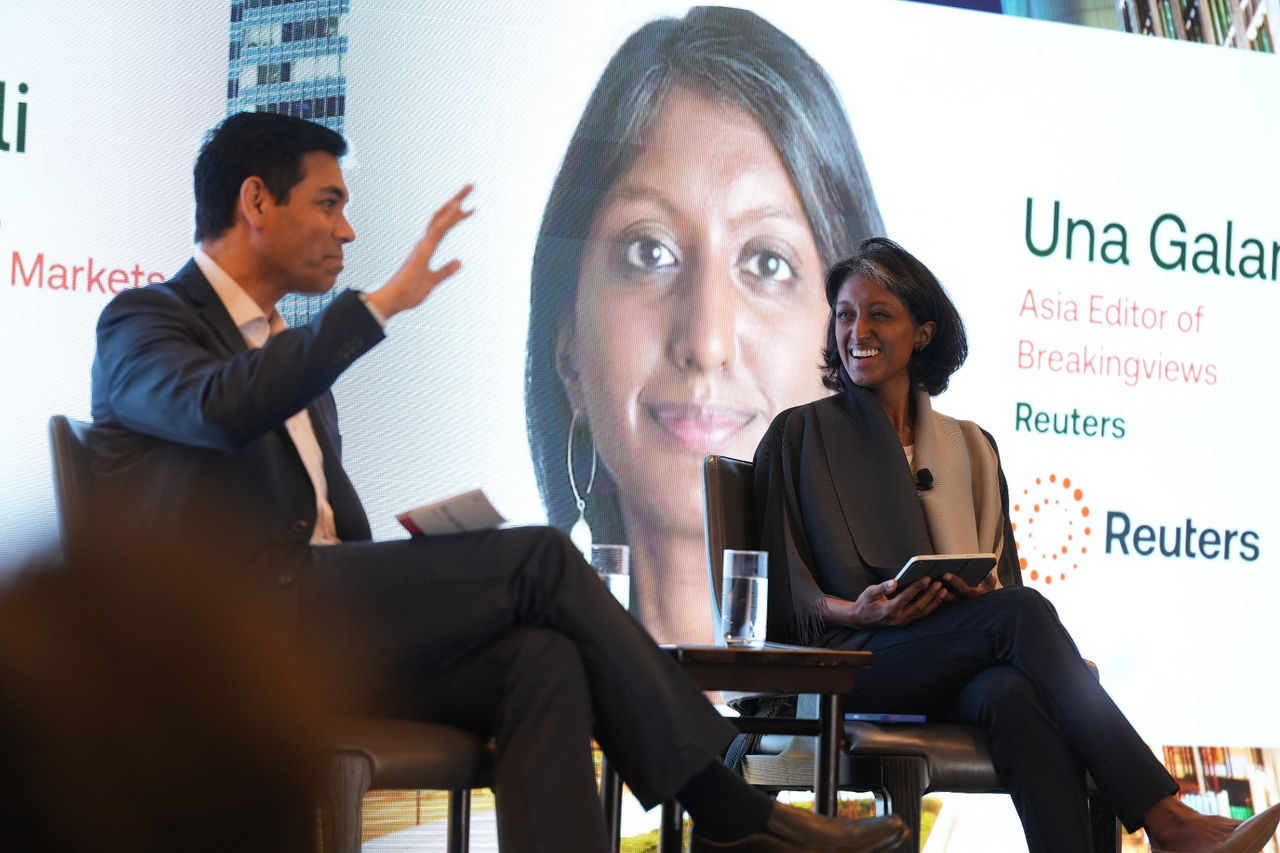 Two speakers seated on stage in front of a large event screen during a discussion at a Thomson Reuters Legal Tech forum.