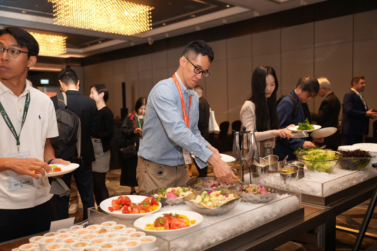 Event attendees serving themselves food at a buffet during a conference networking break.
